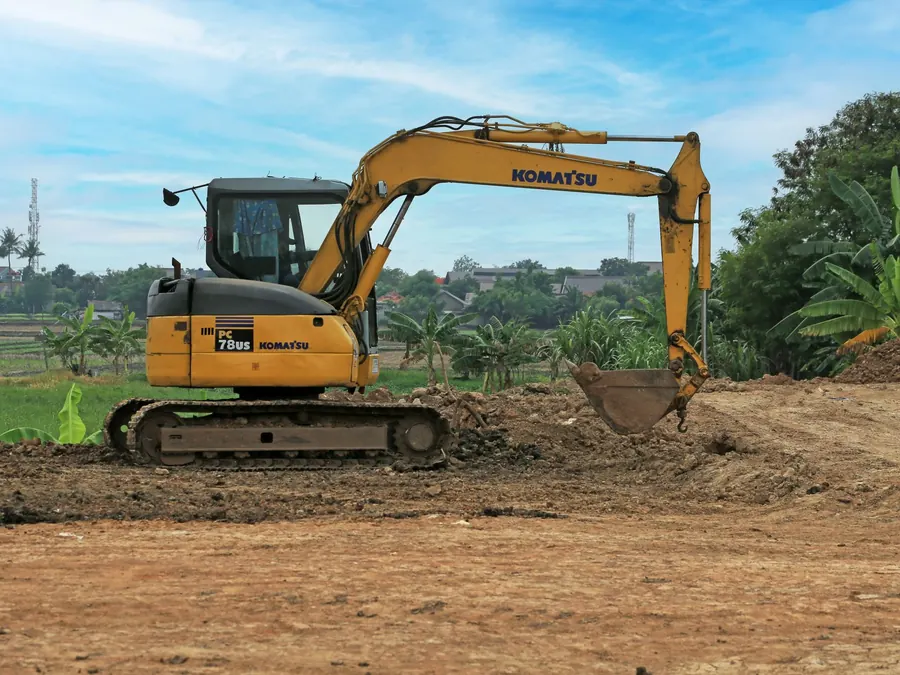 Yellow excavator on a rural construction site on a sunny day.
