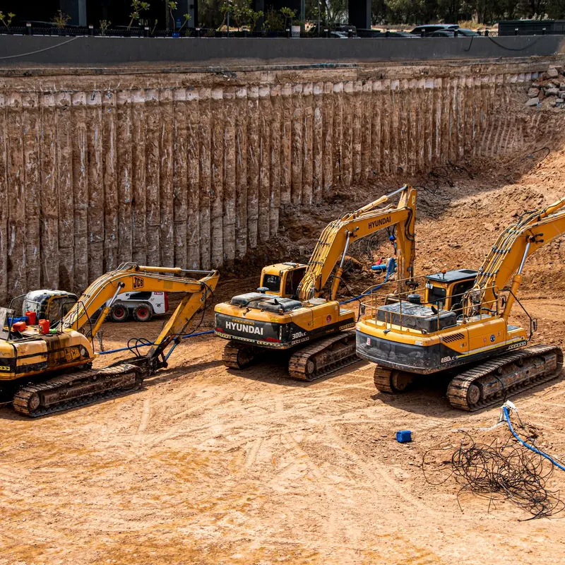 Three excavators working at a construction site for land excavation.