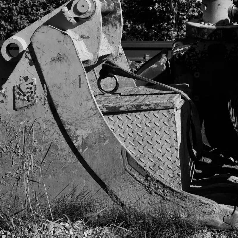 Monochrome image of an excavator bucket in a construction site.