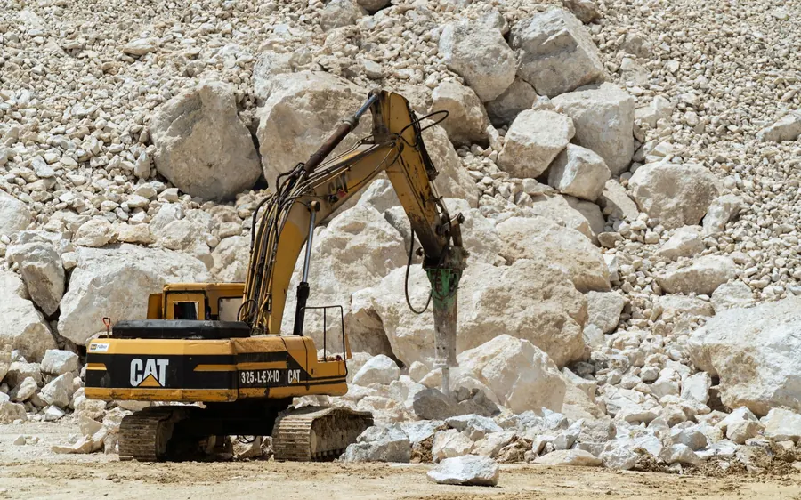 Excavator breaking rocks in a quarry, showcasing heavy-duty industrial work.