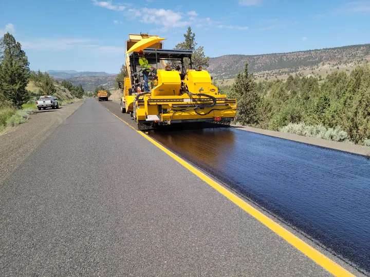 Road construction with paving machine in rural Oregon, highlighting infrastructure development.