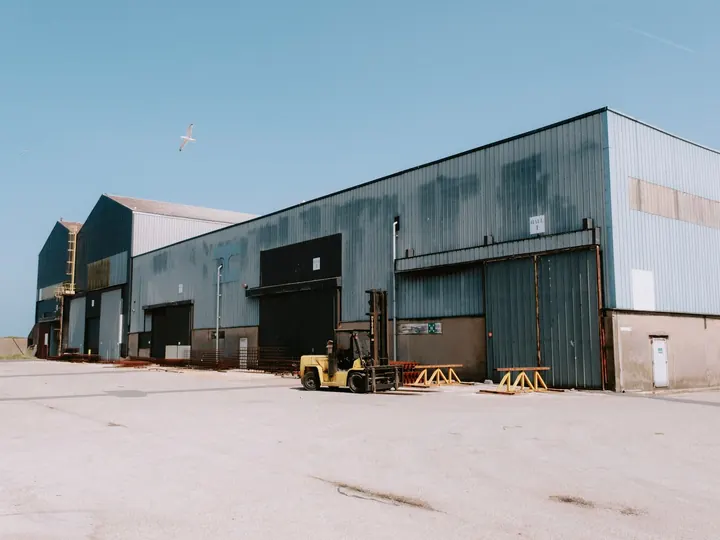 A large industrial warehouse with a forklift and a bird flying overhead.