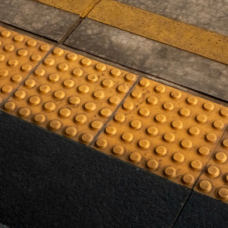 Detailed view of tactile guiding blocks for accessibility at Jakarta train station.