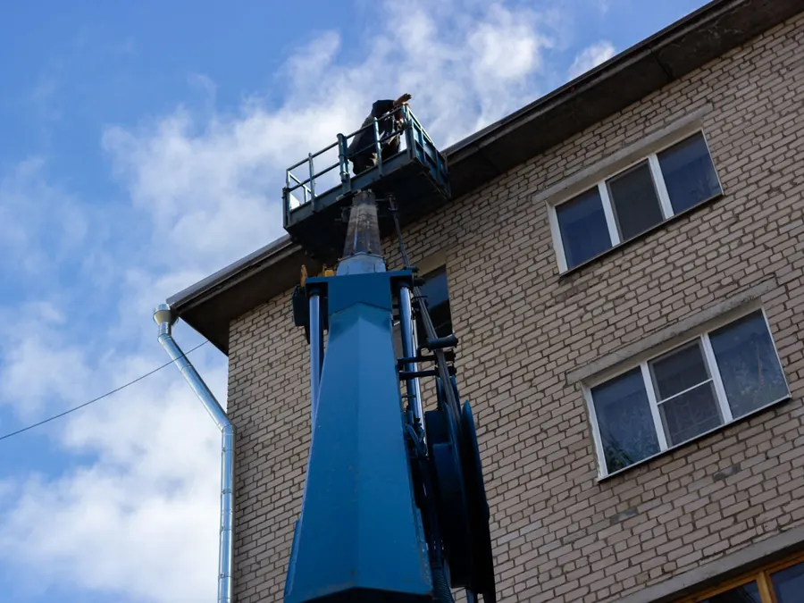 Low angle shot of a brick building exterior with a construction crane reaching the roof.