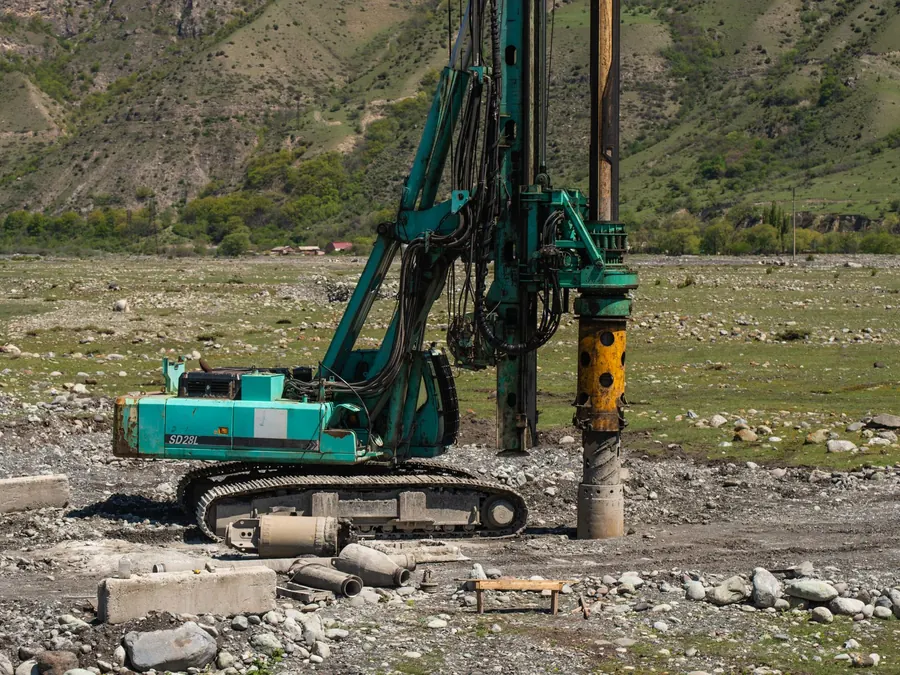 A heavy drilling machine in use on a rugged outdoor construction site.
