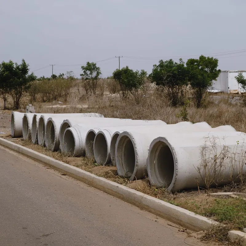 A row of concrete pipes on the roadside in a dry, rural setting.