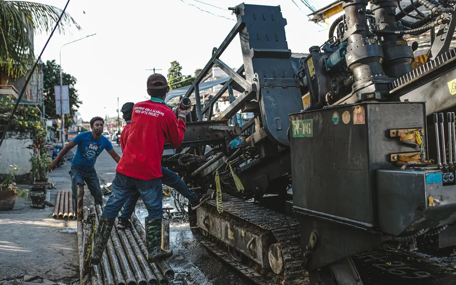 Urban scene of construction workers operating heavy machinery for street drilling.